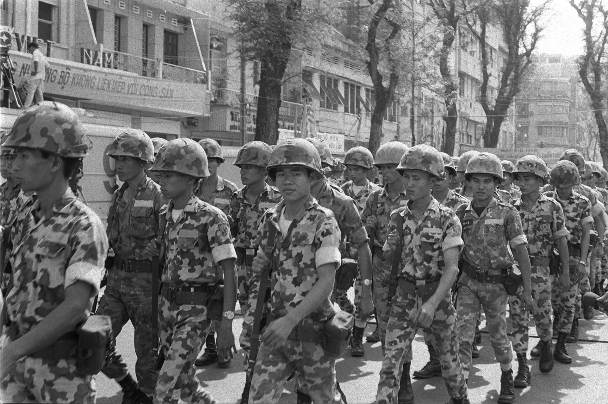 several men in uniform marching down a city street