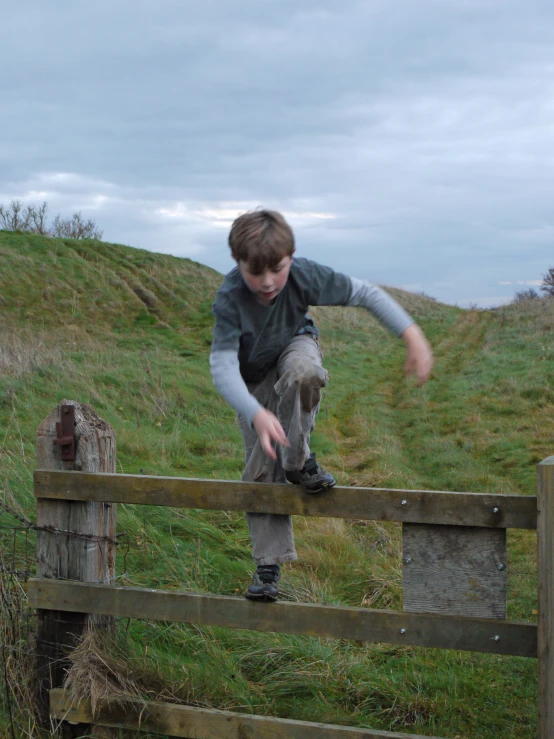 a small boy climbing on top of a fence