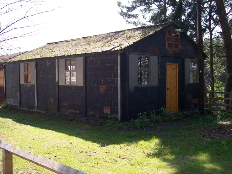 an old brown building with windows has a wooden fence