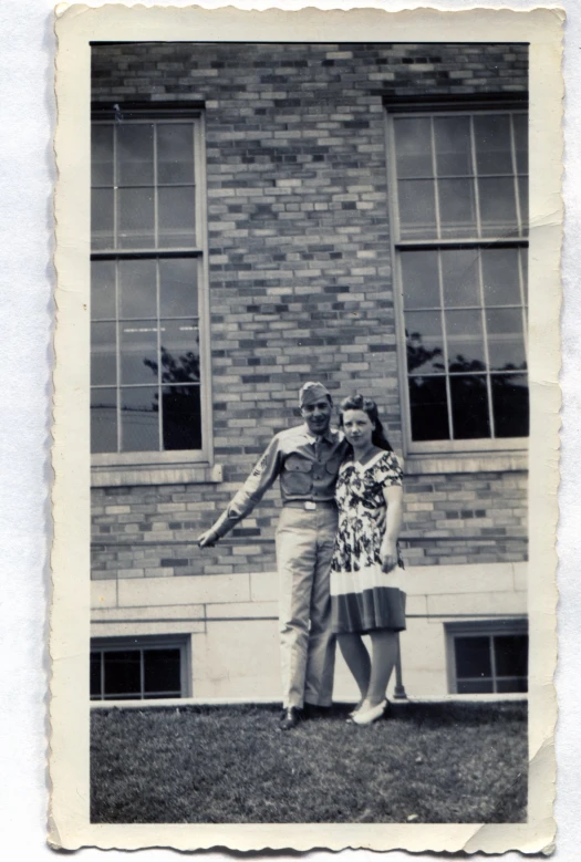 two people posing for a picture in front of a brick building