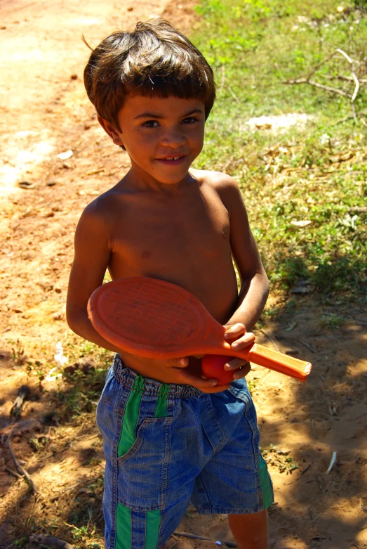 a  holding a plastic racquet on a dirt path