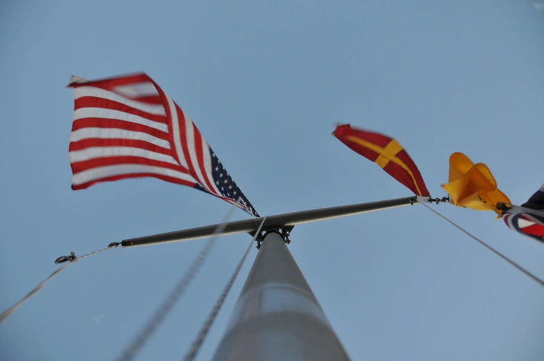 three flags on a pole with sky in the background