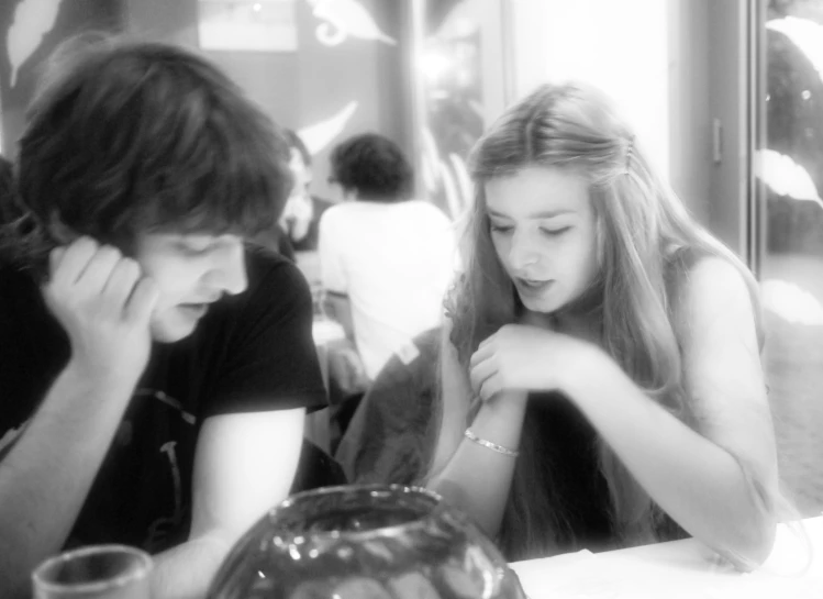 two young ladies sitting in front of a cake