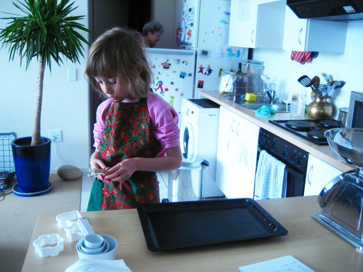 a little girl standing in a kitchen holding soing