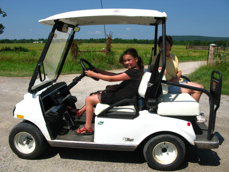 a white golf car with two girls on it