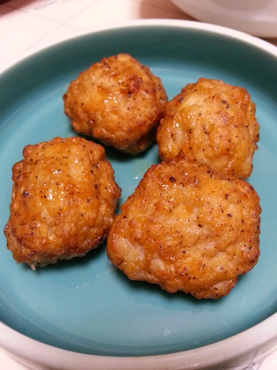 four small meatballs sitting on a blue plate