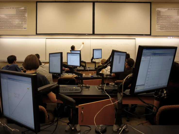 an office full of people sitting in front of computer monitors