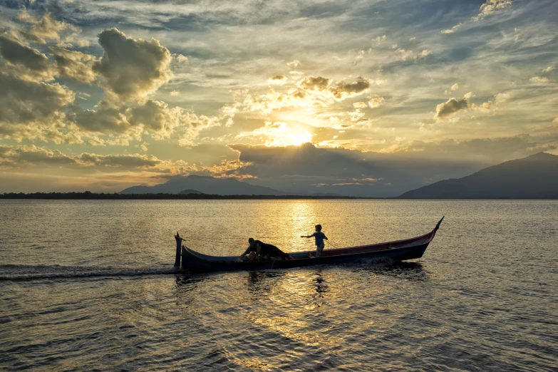 a man stands in a boat as the sun goes down on lake argyle