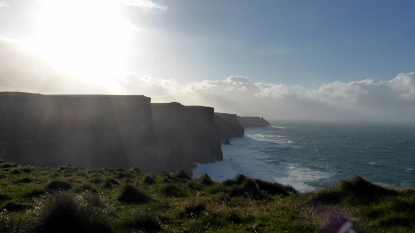 the sun shines on the rocky coast next to the sea