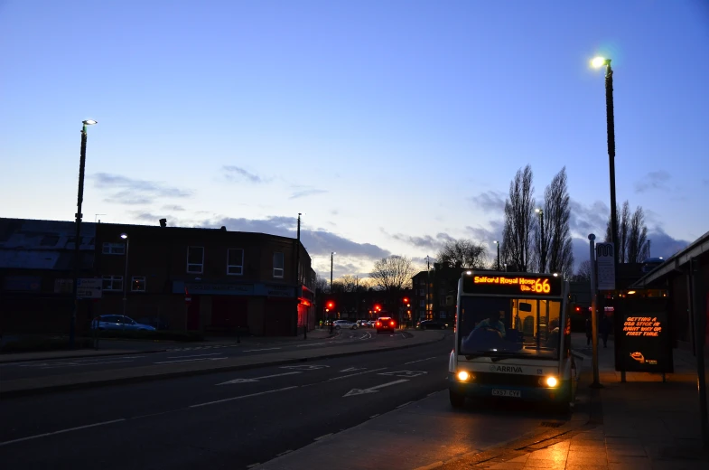 a small bus pulling into a bus stop at night