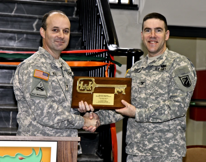 two men in uniform are holding an award