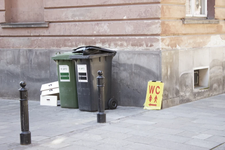 a garbage can on the side of the street with a sign