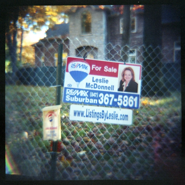 a real estate sign posted on a chain link fence