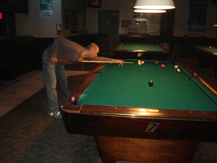 a man stands over a pool table with a wooden stick