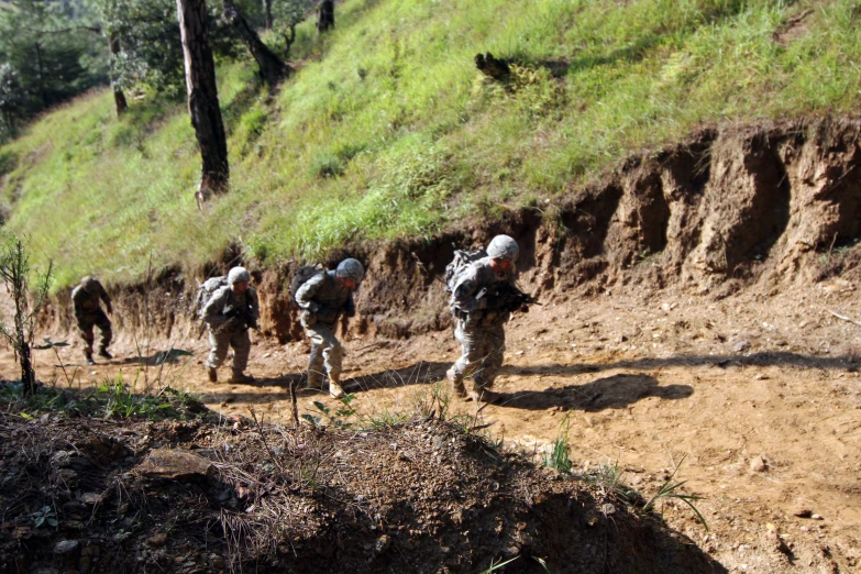 some military men walking up a trail in a line