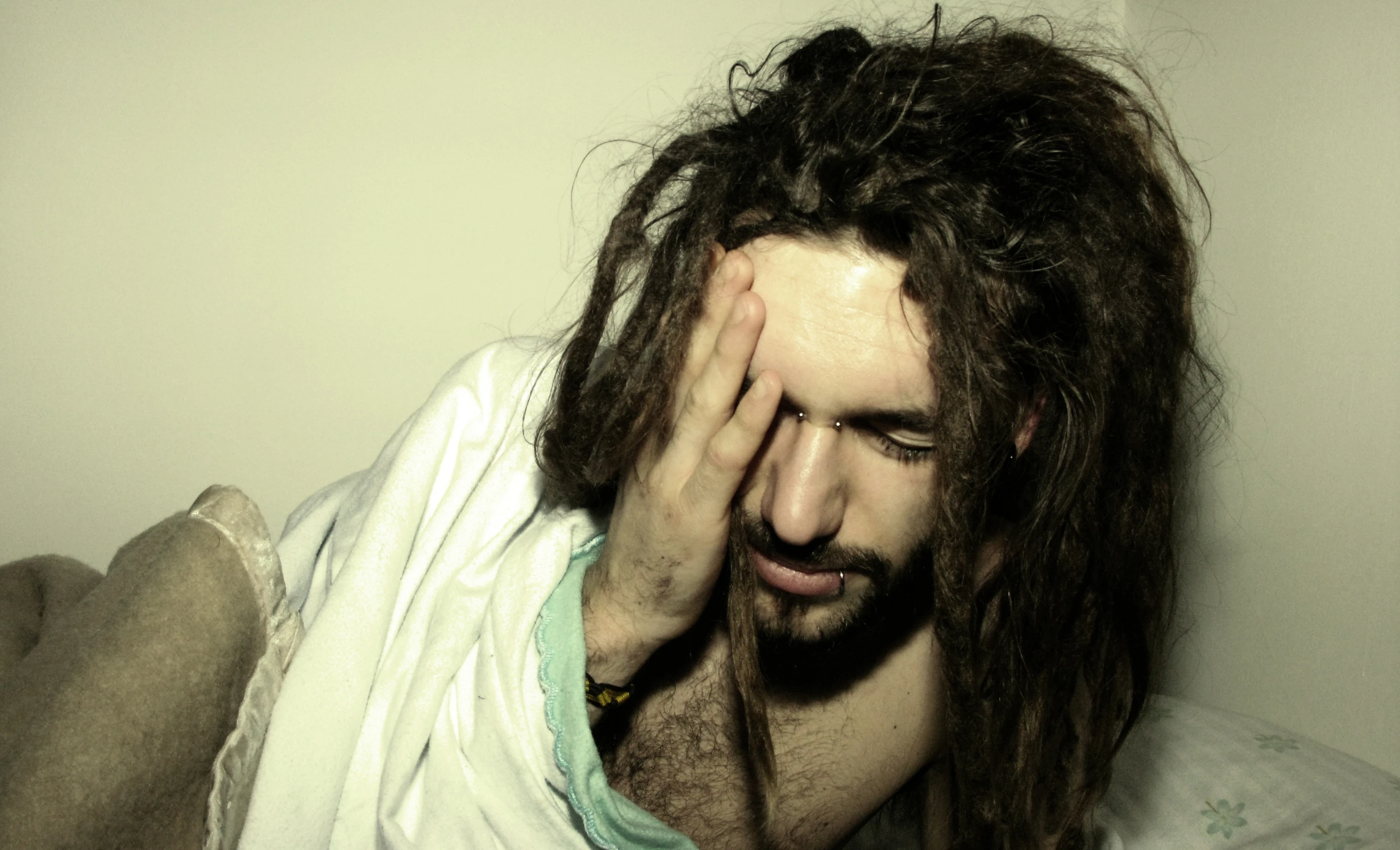 man with long hair covering his face with white cloth