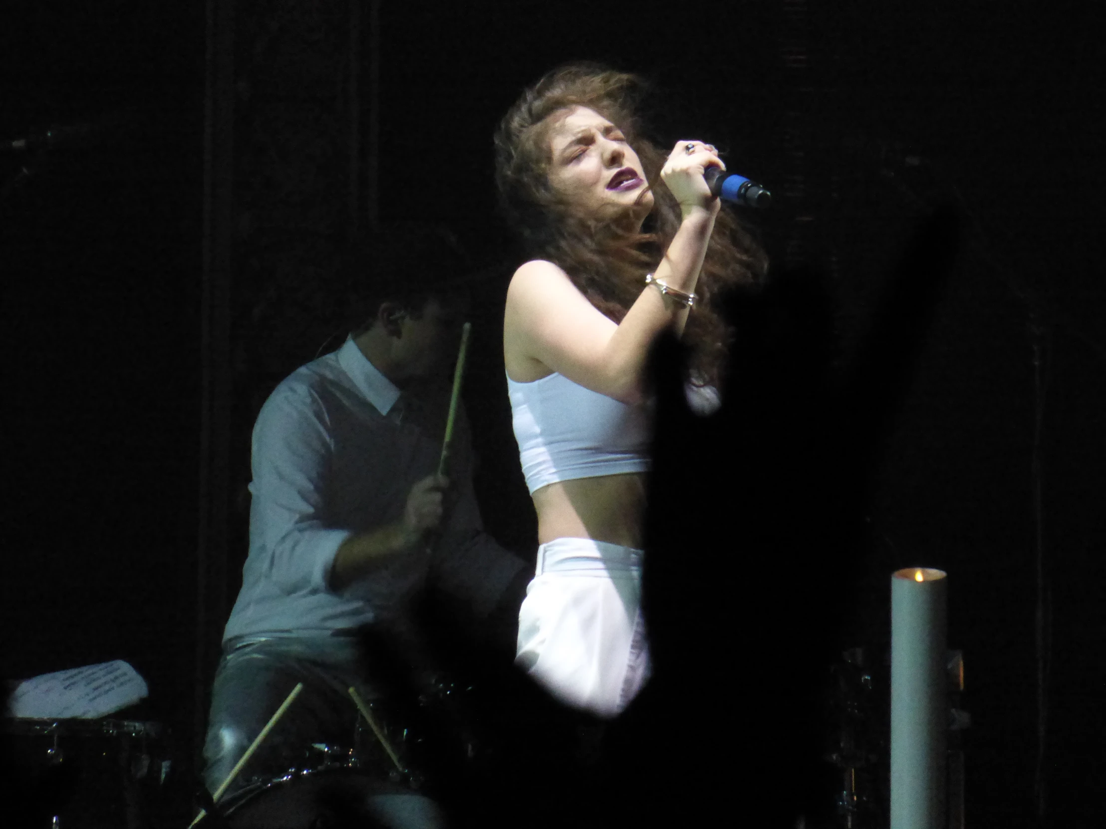 a singer in white clothing performing with other audience