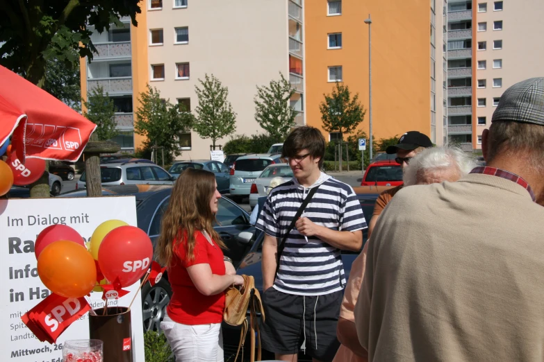 young people chatting outside in the city, some with red and yellow balloons