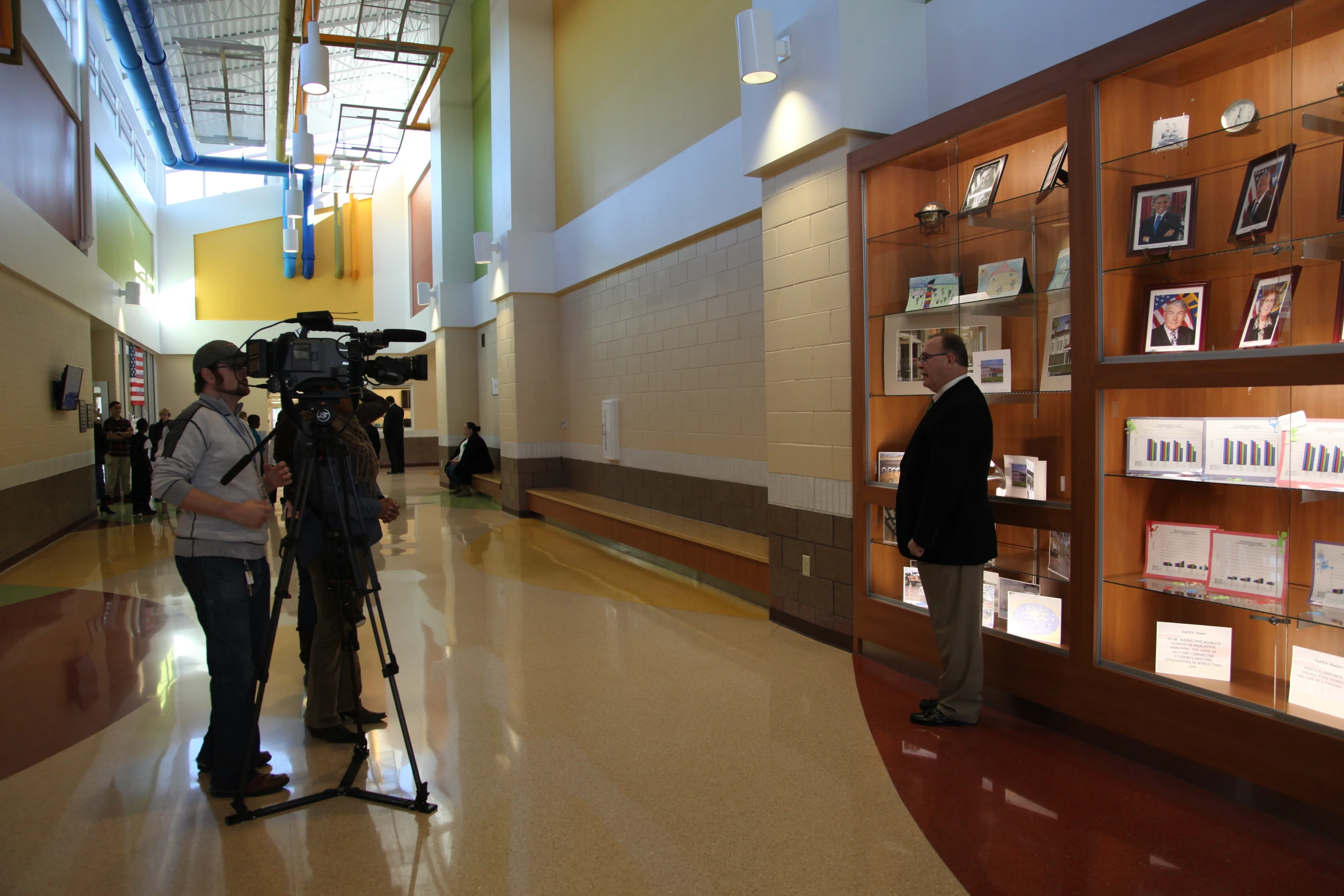 an amateur camera man on tripod filming in large room