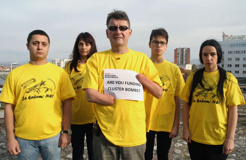 a man holding a sign standing next to five young people