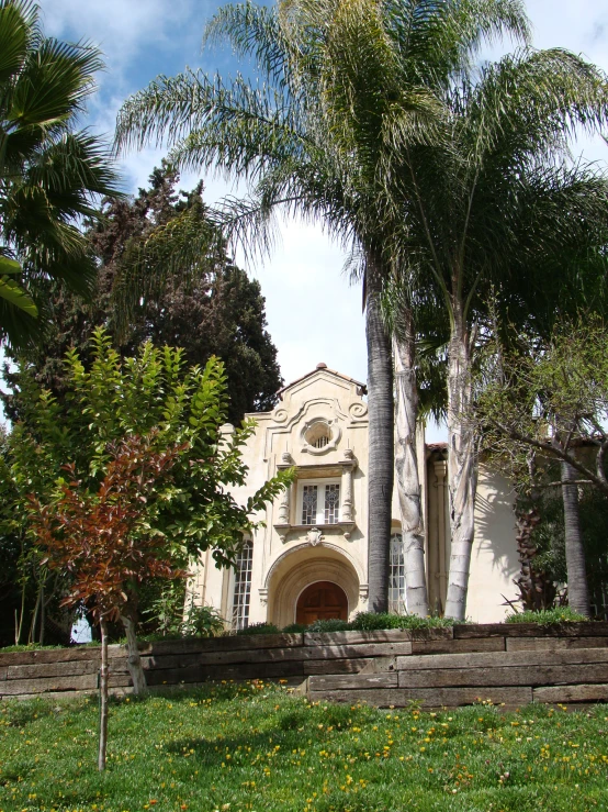 a mansion is shown with trees and some benches