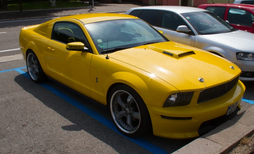 a yellow mustang is parked near several other cars