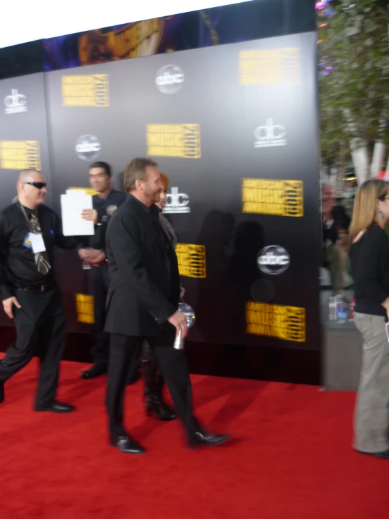 people walking on red carpet with one person in suit holding papers