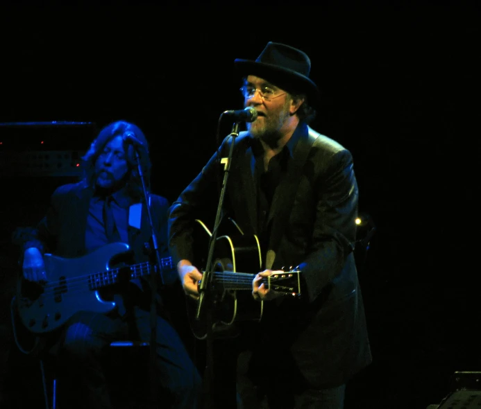 a man that is playing guitar while standing in front of a microphone