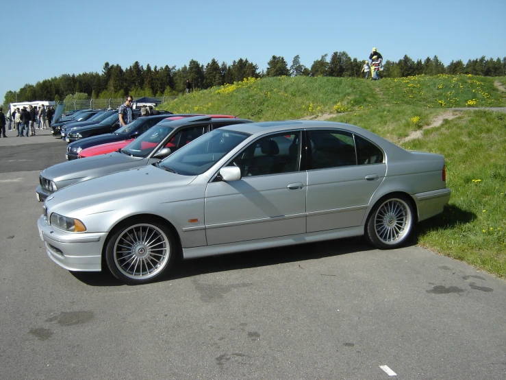 a bunch of parked cars on a field next to a hill