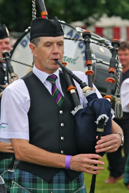 a man in a kilt playing pipebells outside