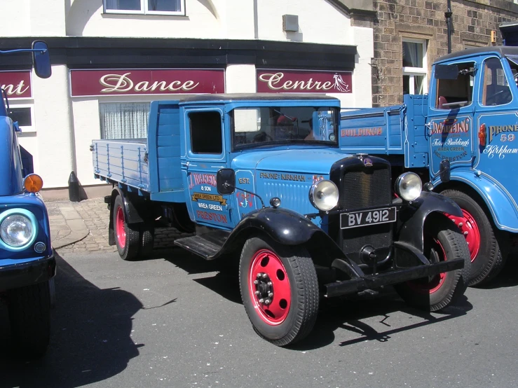 two vintage trucks sitting next to each other in front of a building