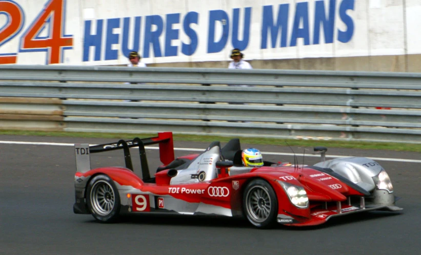 a racing car is on the track beside a stadium