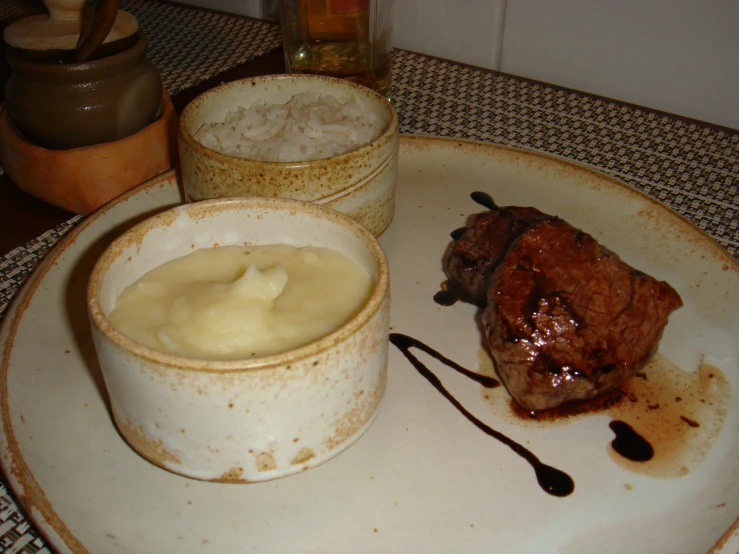 meat and mashed potatoes on a plate next to a beer