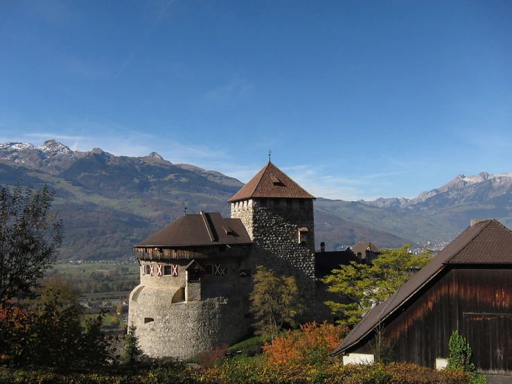 the castle is built on a hill with large mountains in the background