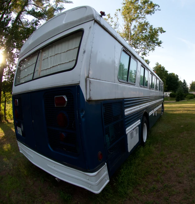 the back end of an old school bus parked in a grassy area