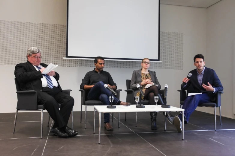 three people are seated and talking on stage