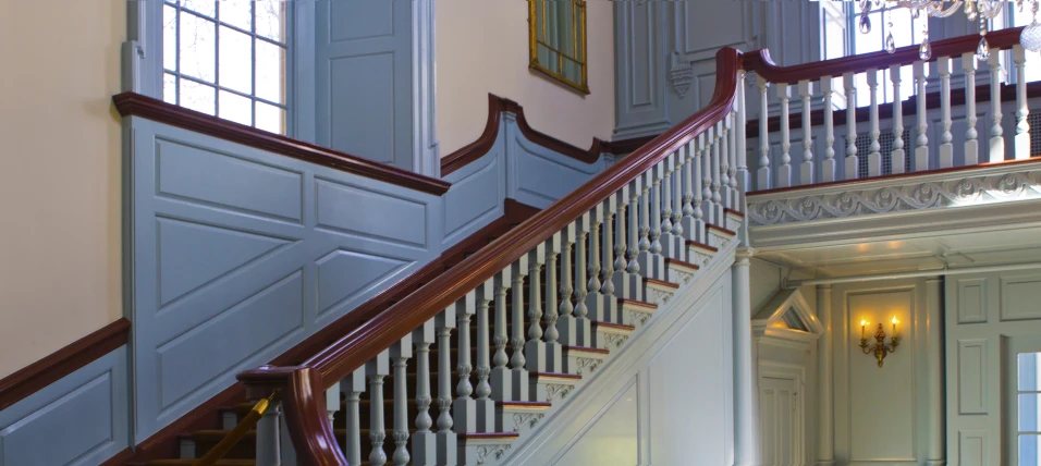 a grand stairway with chandelier and mirror over it