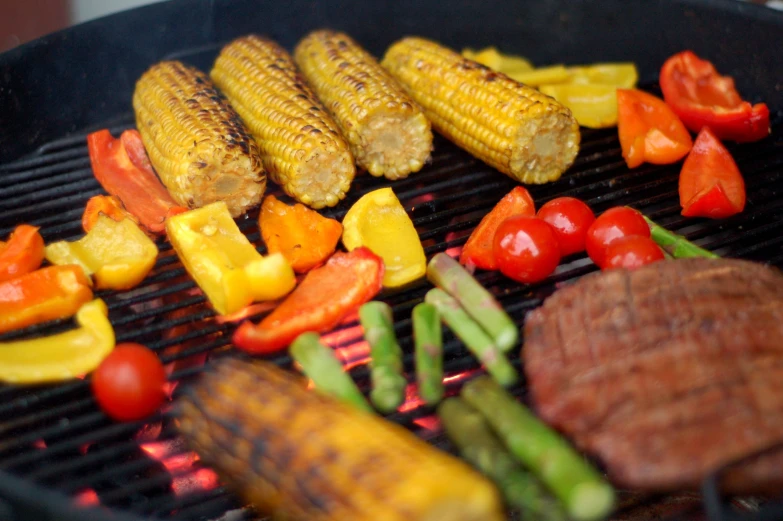 corn, carrots and peppers are cooking on the grill