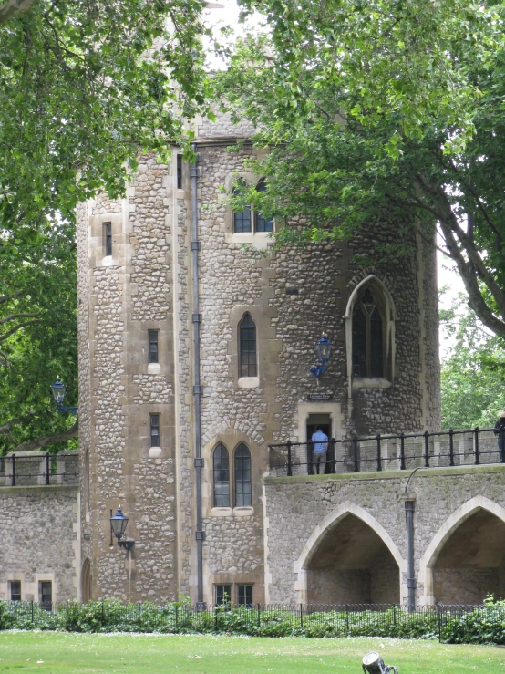 a stone tower has three arches and a balcony above it