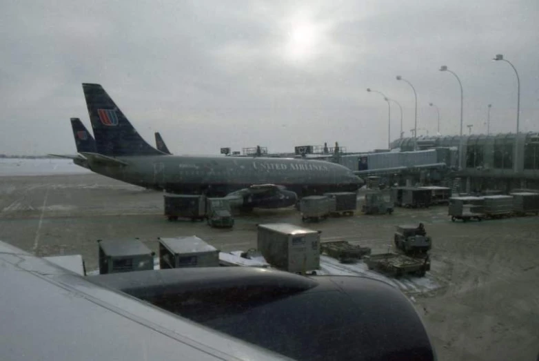 an airplane parked at the terminal where several are waiting for luggage