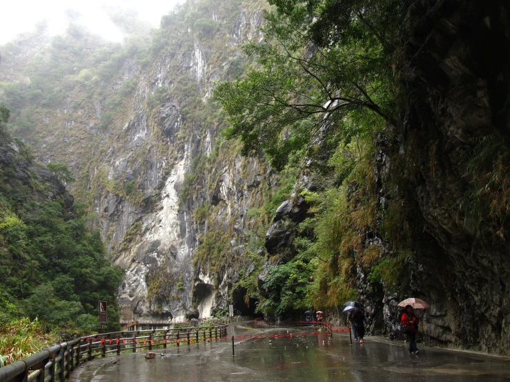 people are walking down a path under a waterfall