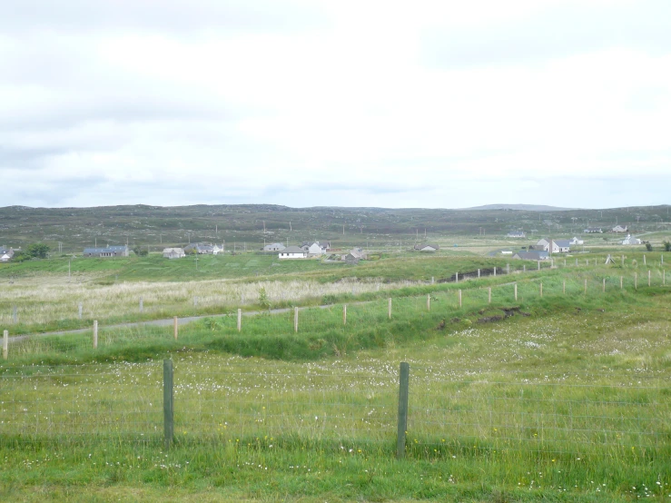 a grassy field next to a fence and buildings