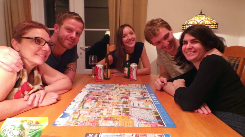 four adults sitting at a table with a large puzzle