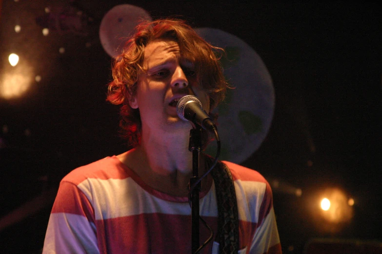 a man in striped shirt singing into a microphone