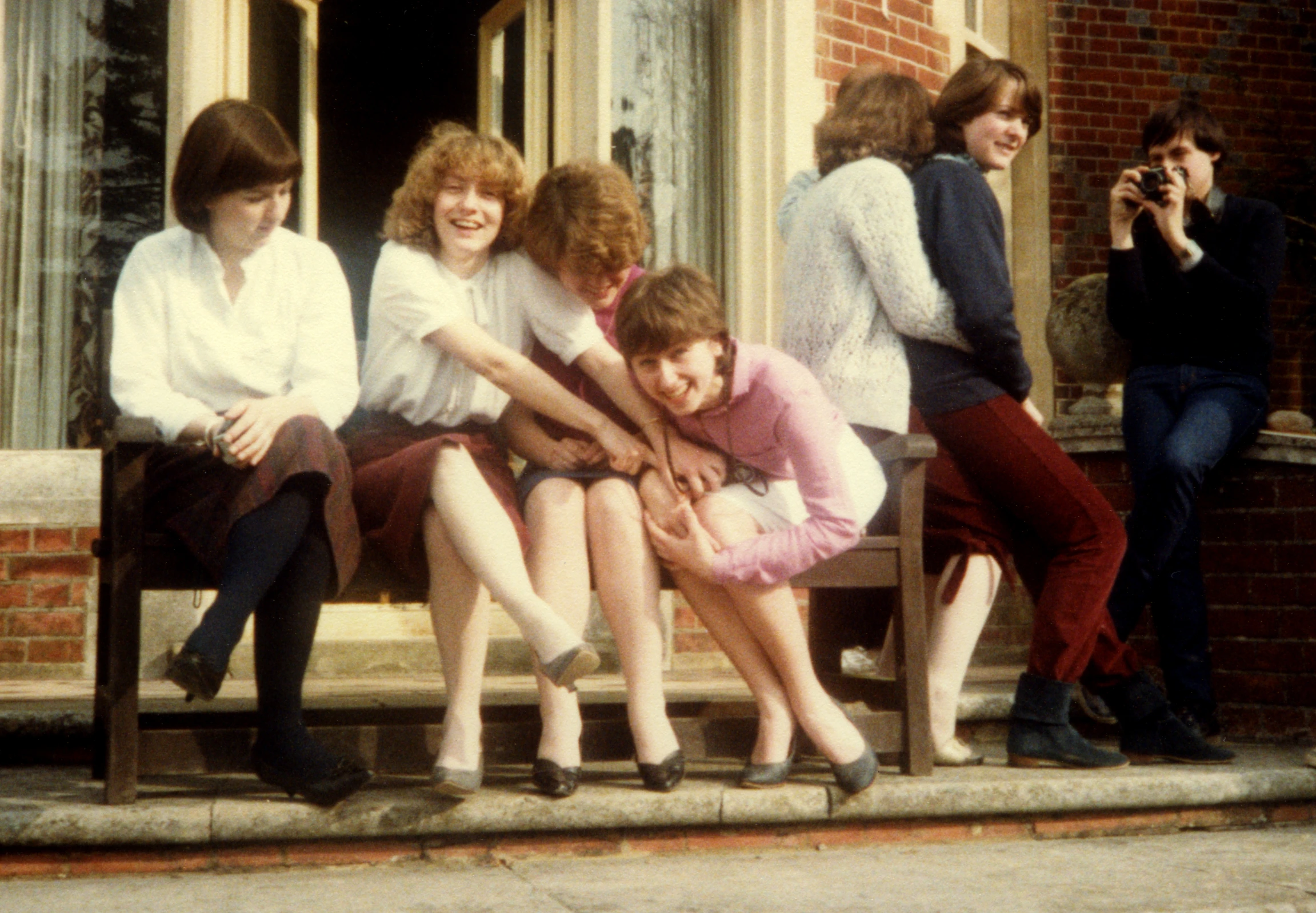 a group of women sitting on top of a wooden bench