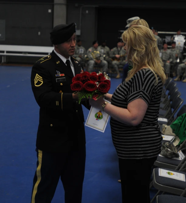 a man and woman standing next to each other in front of military uniforms