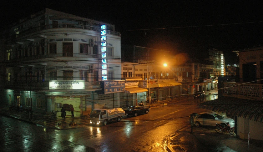 an illuminated building on a wet street at night