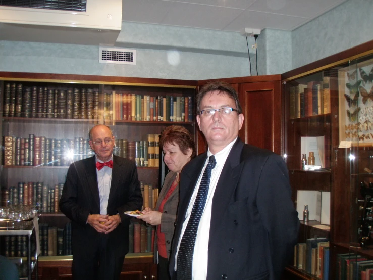 two people standing next to each other in front of a bookcase