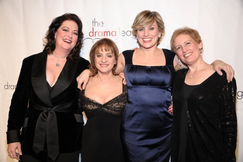 three women pose with one woman in a blue dress
