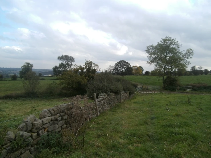 stone wall in the grass next to a brick fence